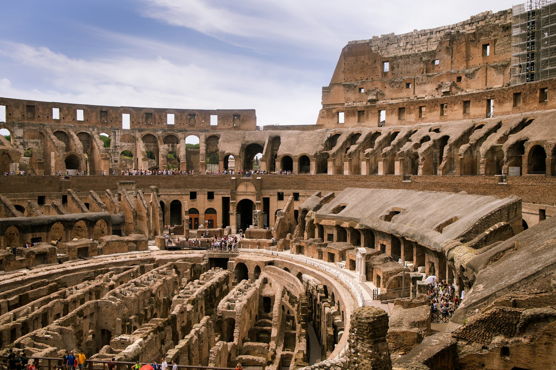 a large ancient building with many people standing around it with Colosseum in the background